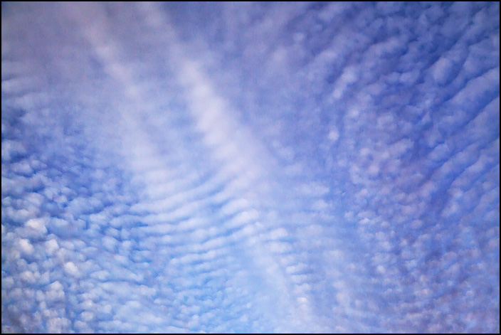 Abstract photograph of a sky with patterns formed by intersecting lines of white and purple clouds.