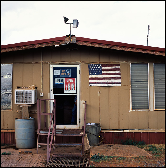 A hand-painted American flag on a sheet of metal hanging next to the door of the 4D Truck Washout and Livestock Rest near Sayre, Oklahoma.