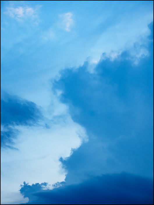 Abstract photograph of dark storm clouds forming in a blue sky over Fort Wayne, Indiana.