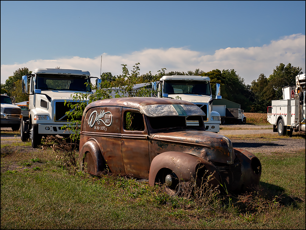 An old rusty 1940 Ford Panel Truck sits in front of Diehls Truck Sales on State Road 6 in rural Noble County, Indiana. The classic automobile serves as a sign for the used truck dealer.
