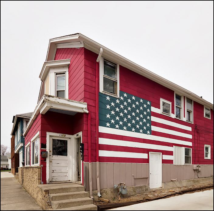 A large American flag painted on the side of an old red apartment house on Delaware Avenue in Fort Wayne, Indiana.