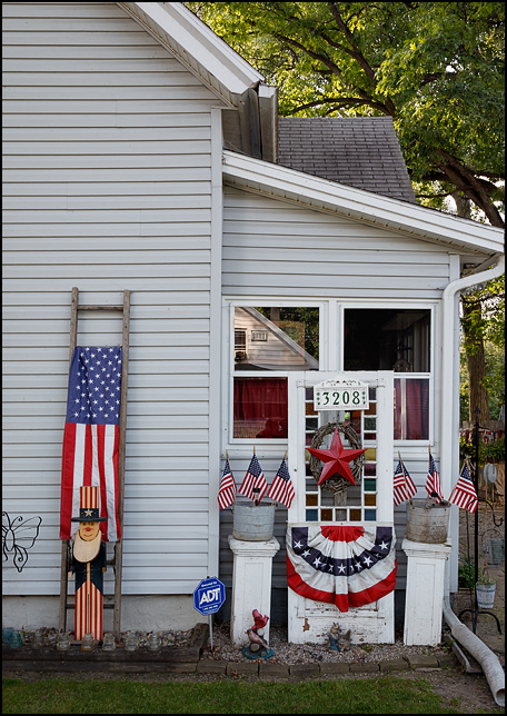 A house decorated with several small American flags, patriotic bunting, and a wooden Uncle Sam on Dinnen Avenue in Fort Wayne, Indiana.
