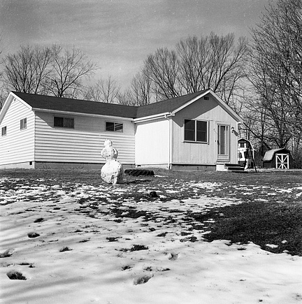 My grandfather's house in winter with a partly melted snowman in the front yard.