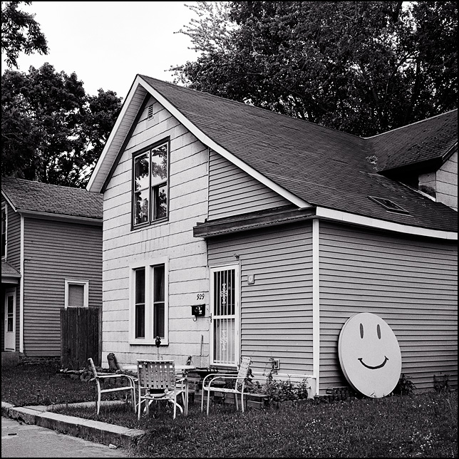 A round table painted like a smiley face leans against the side of an old house on Dewald Street in Fort Wayne, Indiana.