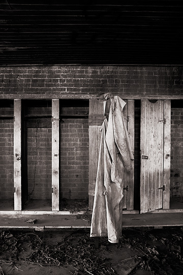 A worker's coveralls still hang from the door on one of the old wooden lockers in the locker room at the abandoned brick factory in Medora, Indiana.