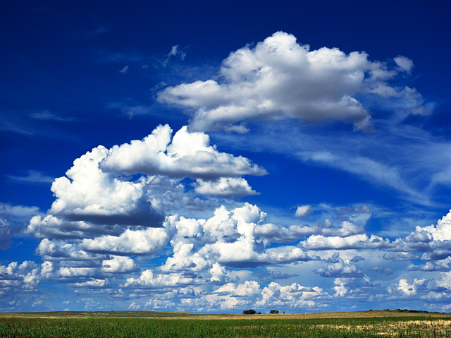 A dramatic blue sky and big clouds over the green plains along Interstate 40 in Quay County, New Mexico just east of the town of Bard.