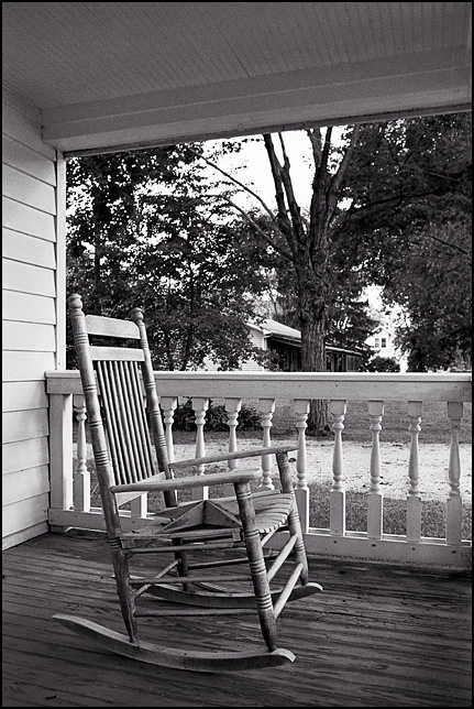 A wooden rocking chair on the front porch of a house in Indiana.