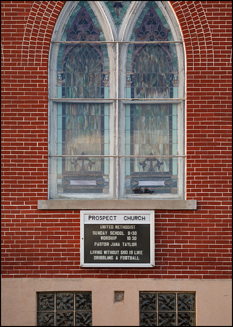Living Without God is Like Dribbling a Football, the sign under the stained glass windows on the front of Prospect United Methodist Church in rural Wells County, Indiana.
