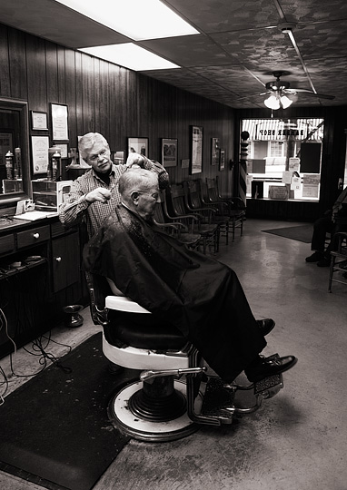 Small town barber Rex Ottinger cuts an elderly gentleman's hair in his barbershop in Roanoke, Indiana. The customer sits in one of the old Koken barber's chairs with enameled armrests and chromed brass fixtures.
