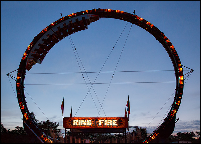 The Ring of Fire carnival ride with its colorful lights in front of a beautiful purple sunset.