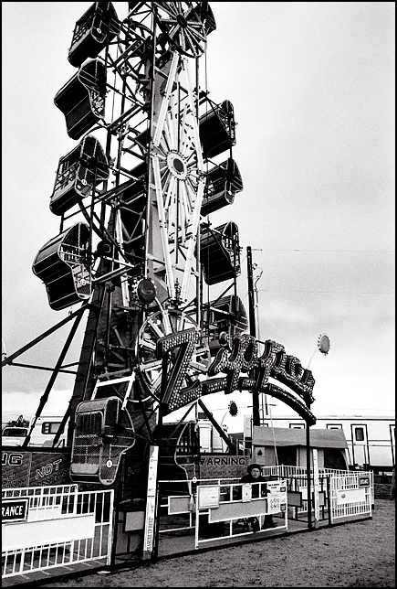 The Zipper Ride at the Rodeo de Santa Fe carnival on a rainy dreary day. The carny looks at me when I take the picture.