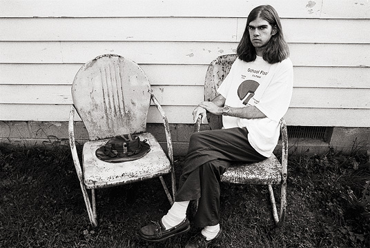 Self portrait of fine art photographer Christopher Crawford sitting on grandpas old rusty metal motel chairs.