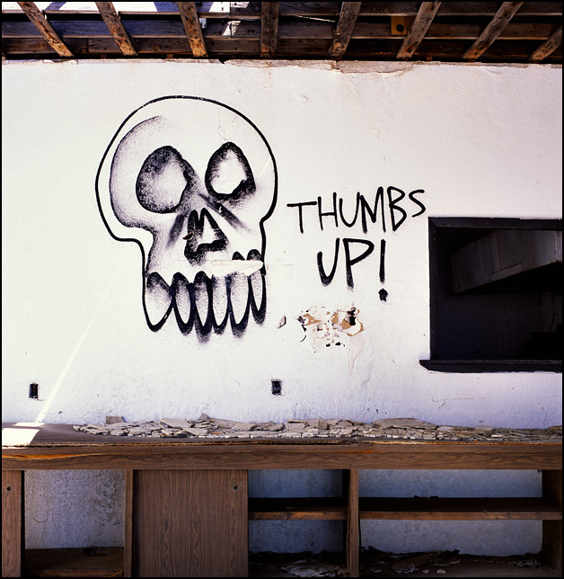Graffiti of a skull and the words Thumbs Up spray painted inside an abandoned restaurant on Route 66 and I-40 in New Mexico.