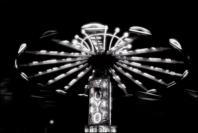 A brightly lit carnival ride called The Yo-Yo in motion at night.