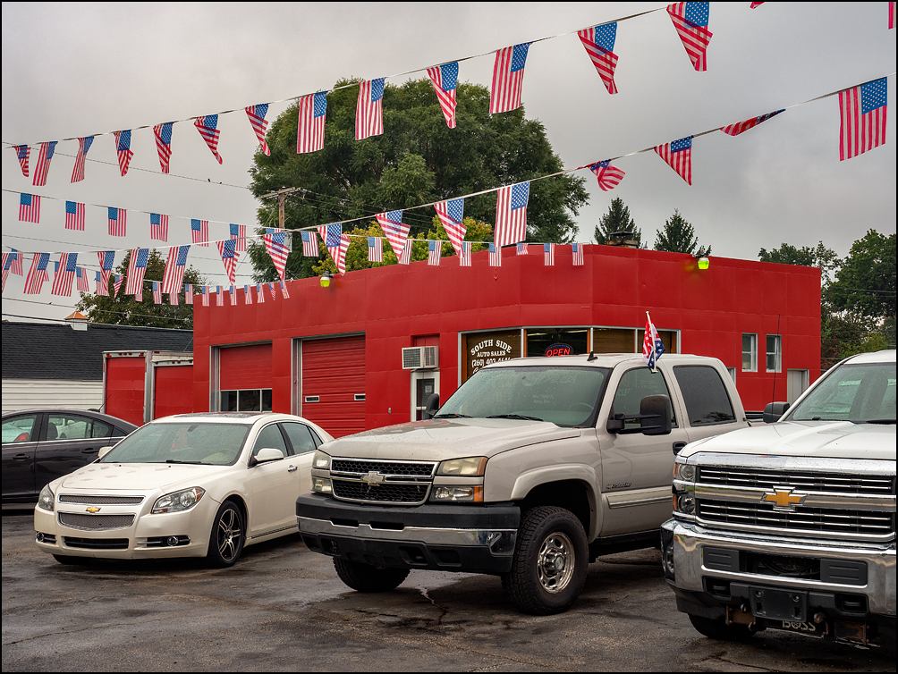 Several long strings of small American Flags crisscross the lot at South Side Auto Sales, a used car dealer on Bluffton Road in the Waynedale area of Fort Wayne, Indiana.