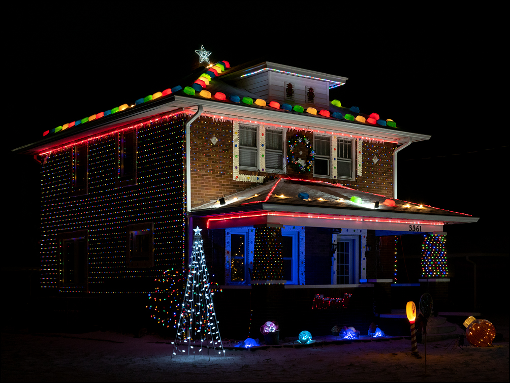 A brick house completely covered in Christmas lights at night, making it look like a gingerbread house. Sandpoint Road in Fort Wayne, Indiana.