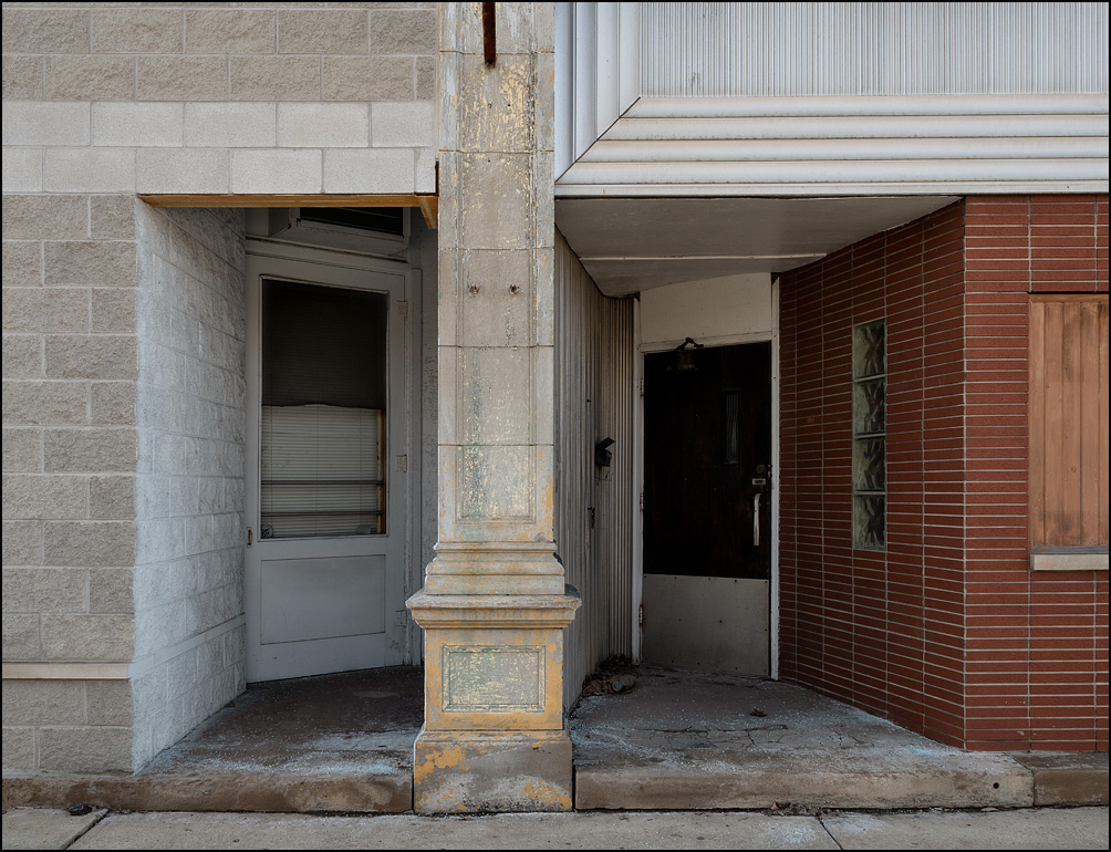 The entrance doors to two adjoining storefronts in the McCavre Building, a vacant building with a cement block and brick facade on Washington Street in the small town of Van Wert, Ohio. One of the storefronts was a bar and pool hall called CJ’s Sidepocket.
