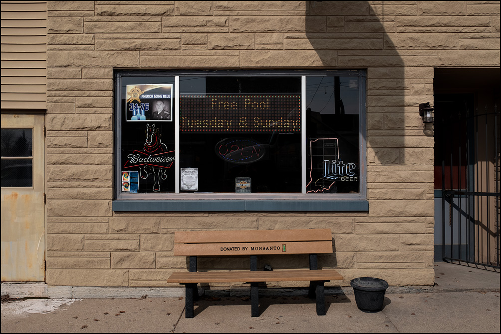 Down On Main Street Bar And Grill in the small town of Greentown, Indiana. A bench in front of the building says it was donated to the town by Monsanto, and the window had neon Miller Lite and Budweiser beer signs.
