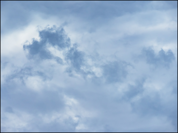 An abstract photograph of patches of dark blue clouds in the early evening sky on a cloudy and rainy day in Fort Wayne, Indiana.