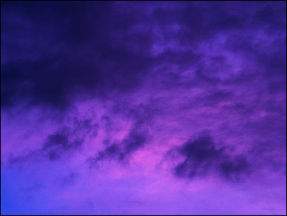 An abstract photograph a row of dark clouds in a purple sky at sunrise in Fort Wayne, Indiana.
