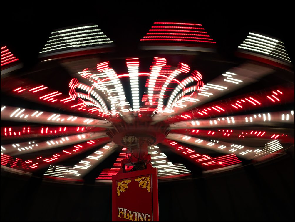 Colorful blurred lights from the motion of the flying circus, a swing carousel ride at the 2023 Three Rivers Festival in Fort Wayne, Indiana.