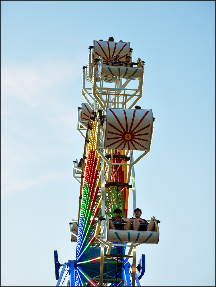 Two boys on the Ferris Wheel at the 2023 Three Rivers Festival in Fort Wayne, Indiana. One of them is looking at his smartphone.
