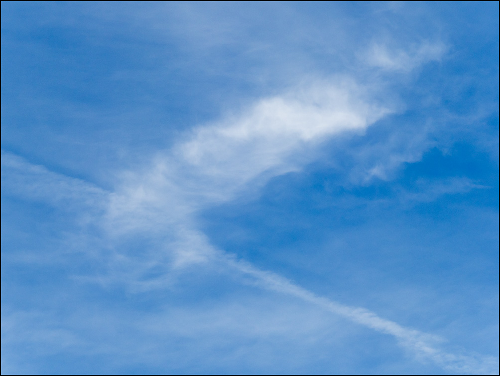 An abstract photograph of linear white clouds intersecting in a blue sky in the evening in Churubusco, Indiana.