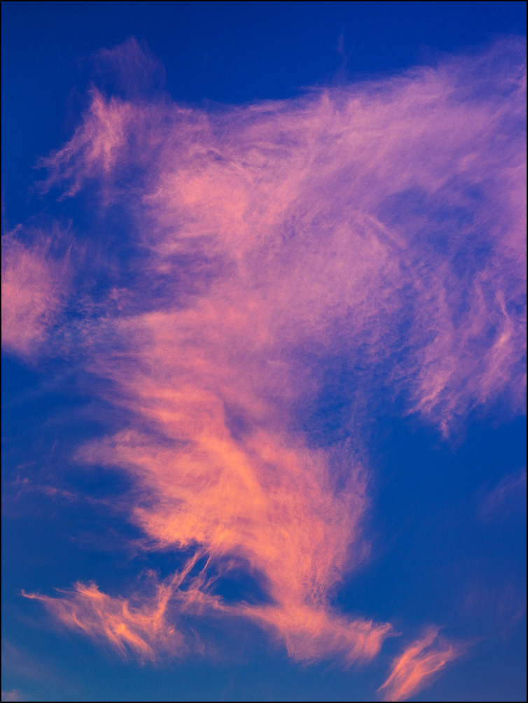 An abstract photograph of red clouds dancing in a purple sky at sunset in Churubusco, Indiana.