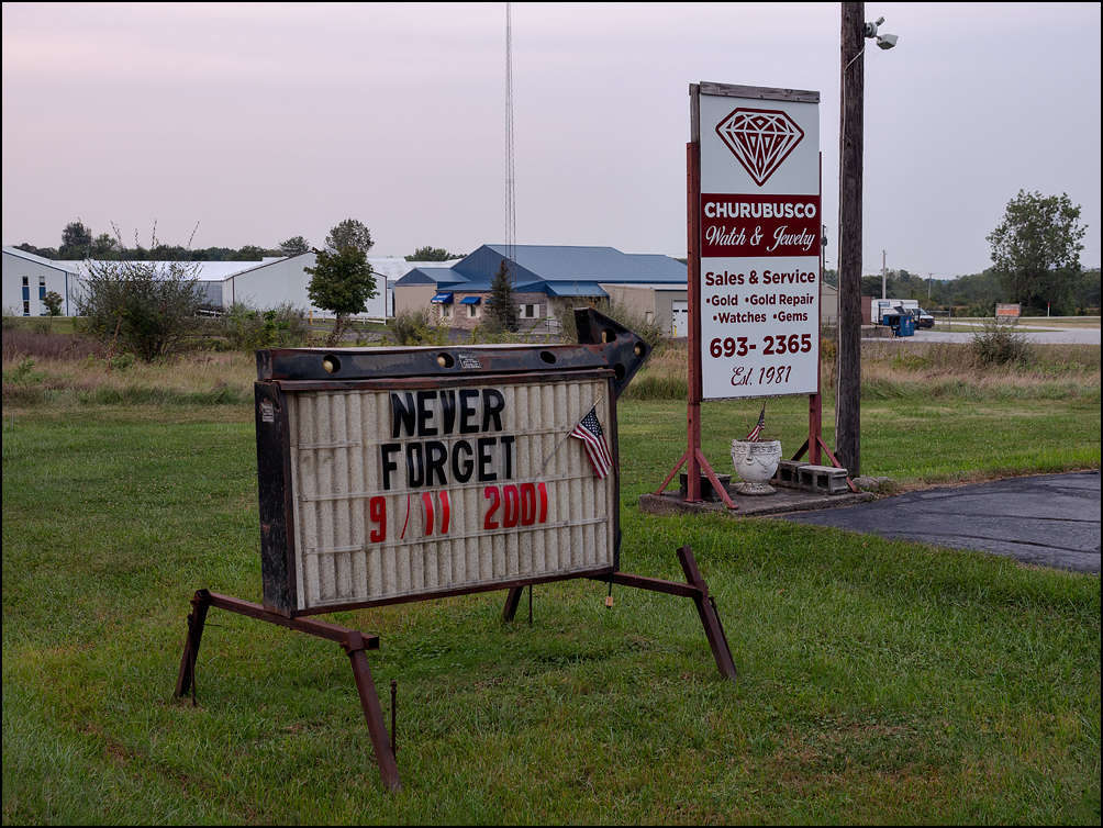 An arrow sign with an American flag commemorating the 20th anniversary of the September 11 terrorist attacks stands in front of Churubusco Watch and Jewelry on US-33 just outside the small town of Churubusco, Indiana.