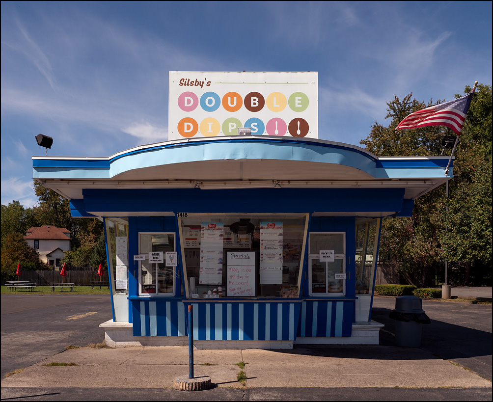 Silsbys Double Dips, an ice cream stand on Main Street in the small town of Medina, New York. The small blue and white striped building has an American flag flying from the roof.
