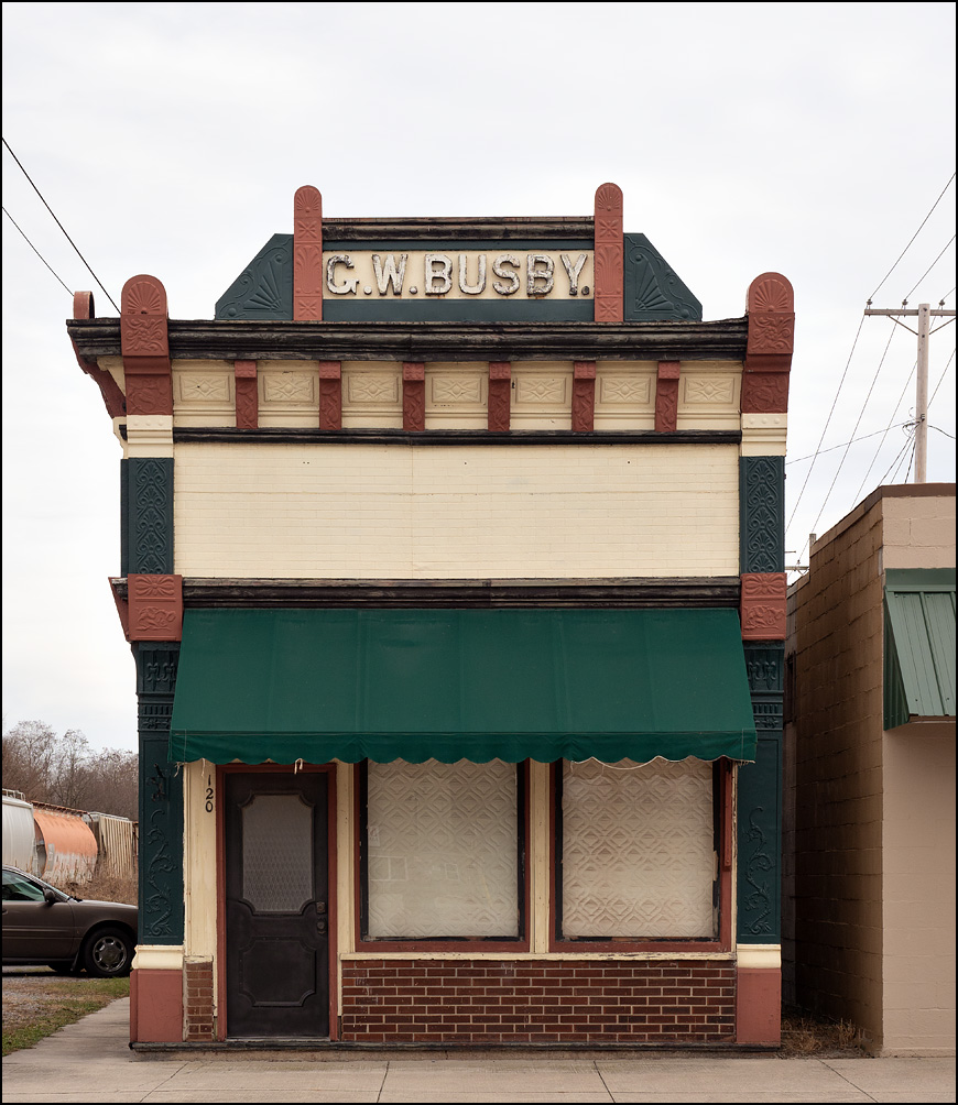 The C.W. Busby Building on Main Street in the small town of Antwerp, Ohio. The small brick storefront has a fanciful gable stone and carved decorations on the top of the building.