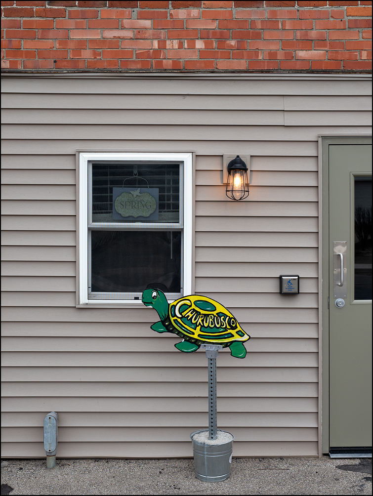 A sign shaped like a turtle stands next to the entrance of the Utilities Office in the small town of Churubusco, Indiana.