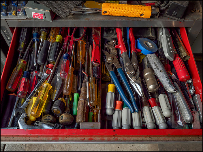 The top drawer of my fathers old red Craftsman tool chest. The drawer is open, and filled with screwdrivers, wrenches, and other hand tools.