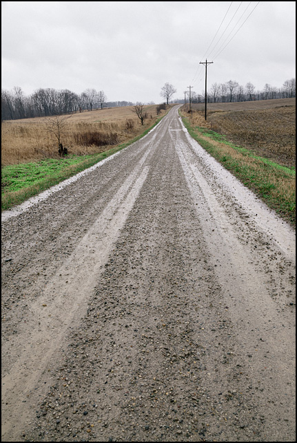 County Road 70, a gravel road flanked by fields on a rainy morning in rural Dekalb County, Indiana.