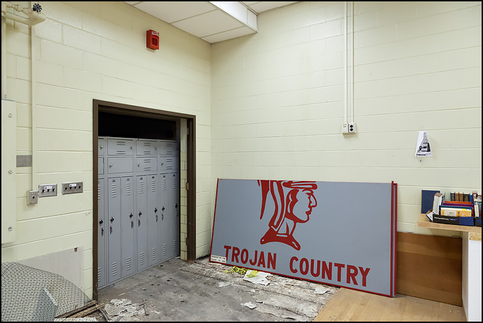 A sign from the gymnasium that says Trojan Country leans against a wall during the pre-demolition sale held at Elmhurst High School on January 27, 2018. A plaque on the sign says that the Class of 1982 donated it to the school.