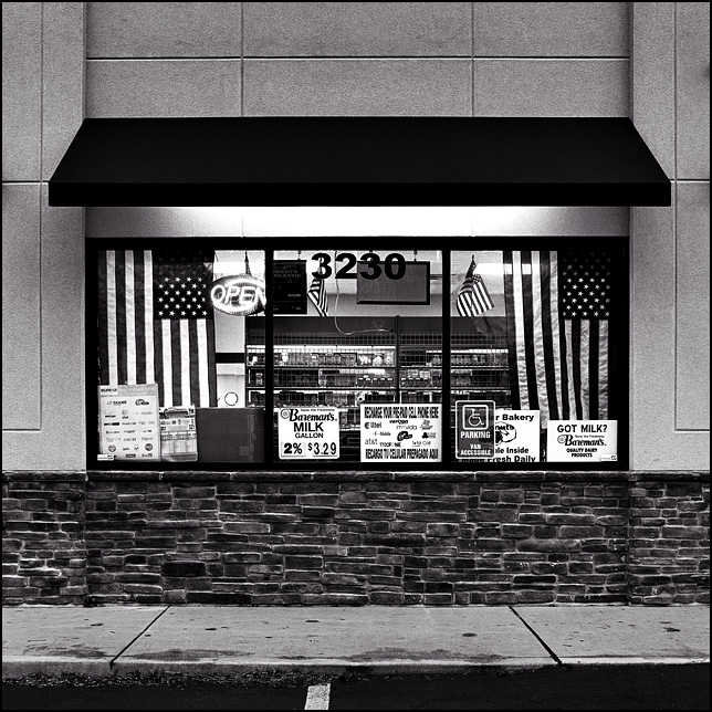 Several American flags hang in the window of a Marathon gas station owned by Asian immigrants on Fairfield Avenue in Fort Wayne, Indiana.