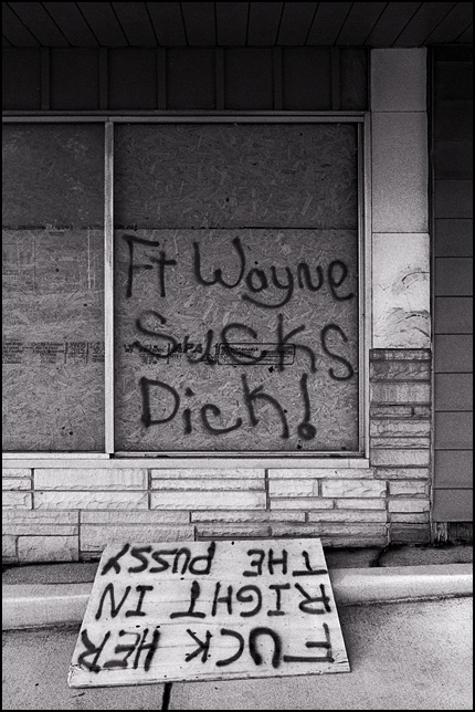Graffiti on a boarded up storefront on Fairfield Avenue in Fort Wayne, Indiana. Fort Wayne Sucks Dick! Fuck Her Right In The Pussy.