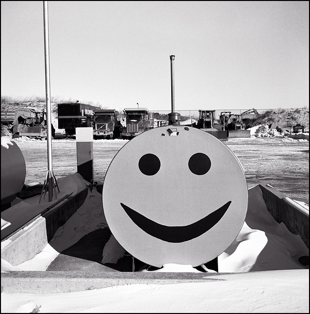A smiley face painted on the end of a large fuel tank in a construction company yard.