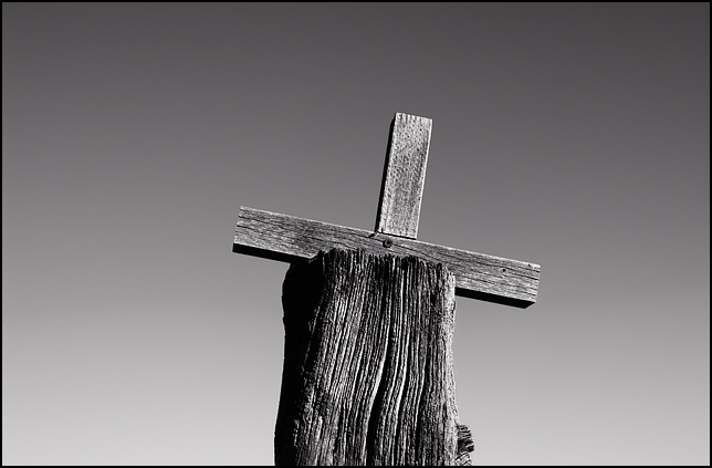 One of the old weathered wood crosses on the top of the stone wall around the cemetery in Galisteo, New Mexico.
