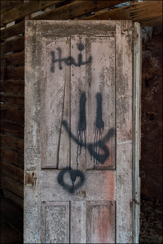 Hai, a heart, and a smiley face with the tongue sticking out. Graffiti on an old weathered wood panel door inside a barn at an abandoned farm on Lower Huntington Road in rural Allen County, Indiana.