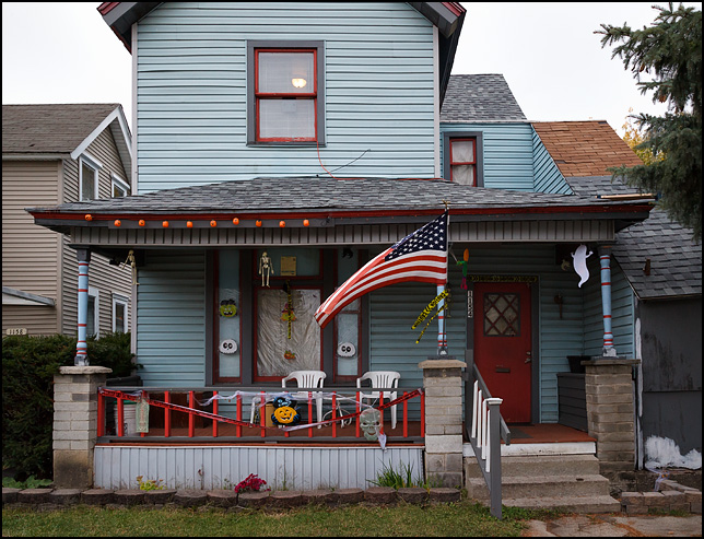 An American flag on the front porch of an old house decorated for Halloween on West Main Street in Fort Wayne, Indiana.