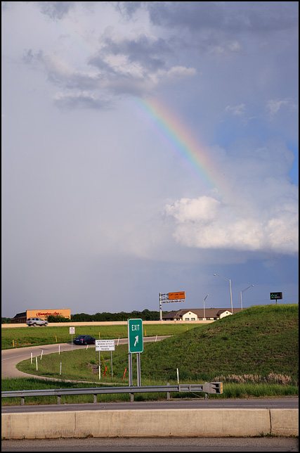 A rainbow between two clouds in the evening sky over the US-24 and I-69 interchange in Fort Wayne, Indiana.