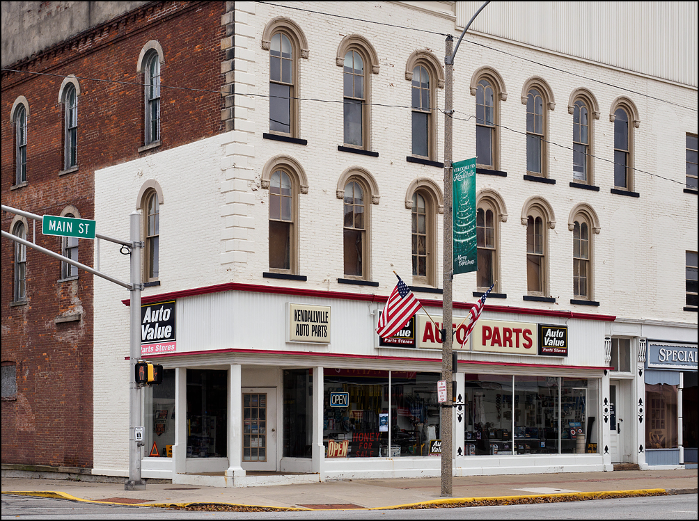 Kendallville Auto Parts is an Auto Value Parts store in an old brick commercial building on Main Street in the small town of Kendallville, Indiana. American flags fly from the light pole in front of the building.