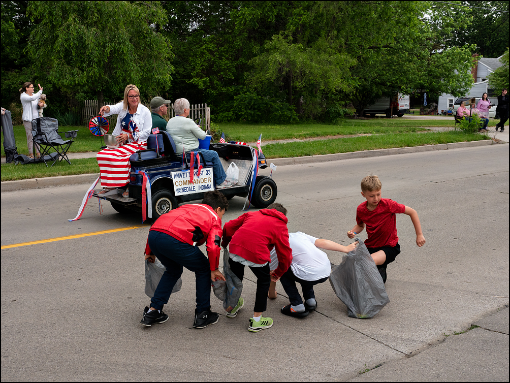 Kids scramble to grab candy thrown to them by a woman wearing an American flag dress at the 2021 Waynedale Memorial Day Parade.