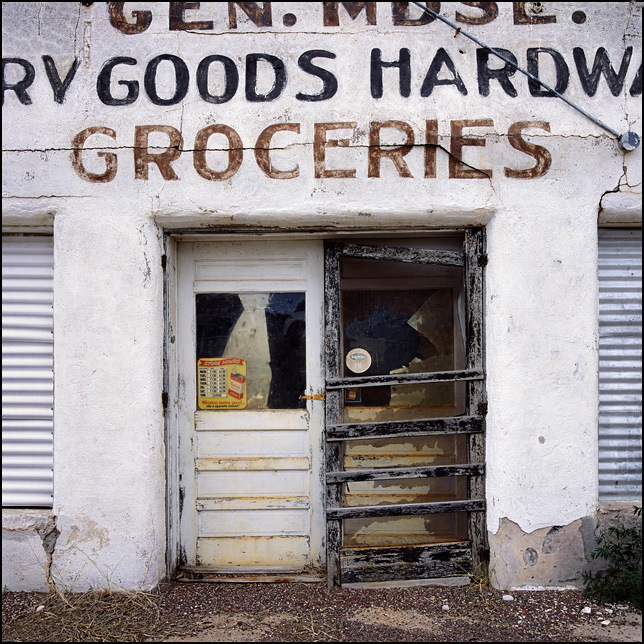 The front doors and adobe facade of the abandoned Tom Montoya Son Grocery and Dry Goods store on US-285 in Encino, New Mexico.