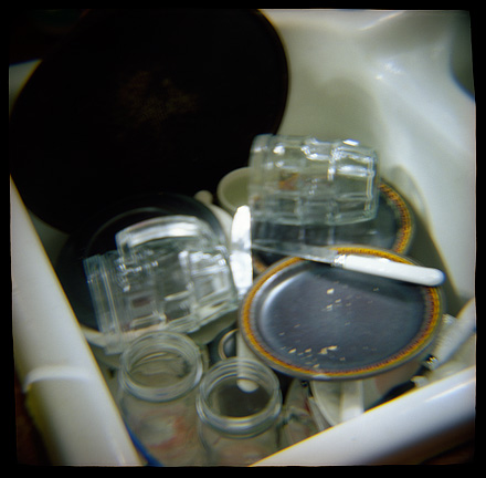 Dirty plates and drinking glasses in the sink, photographed with a Diana toy camera.