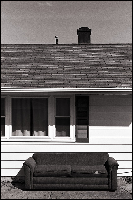 A sofa sits on the sidewalk under the front windows of a house on Oneida Street in Fort Wayne, Indiana.