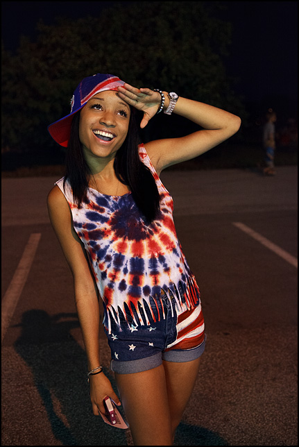 A young woman wearing patriotic clothes and American flag denim shorts at the Fourth of July fireworks in Fort Wayne, Indiana.