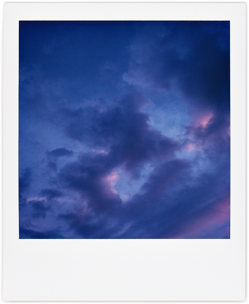 Polaroid abstract photograph of a dark cloud that looks like the outline of a square in the early morning sky.