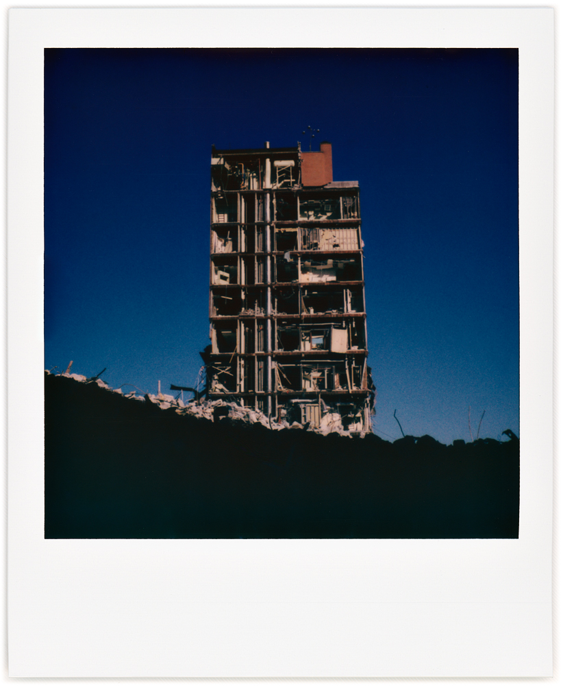 A Polaroid photo of the partially demolished Saint Joseph Hospital in downtown Fort Wayne, Indiana. The interior rooms and corridors of the eleven story building are visible because the rest of the building has been removed.